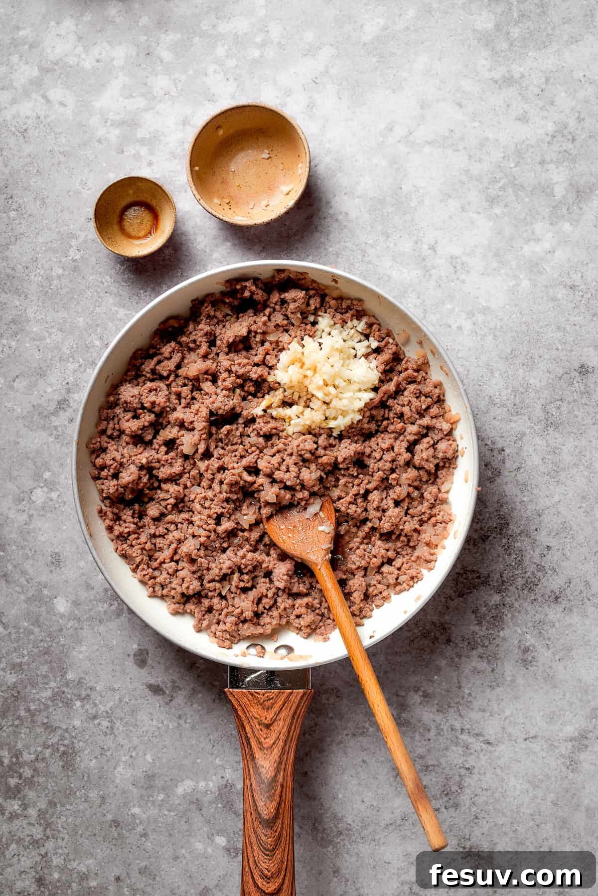 Ground beef being browned in a skillet with a spatula, breaking it into smaller pieces.