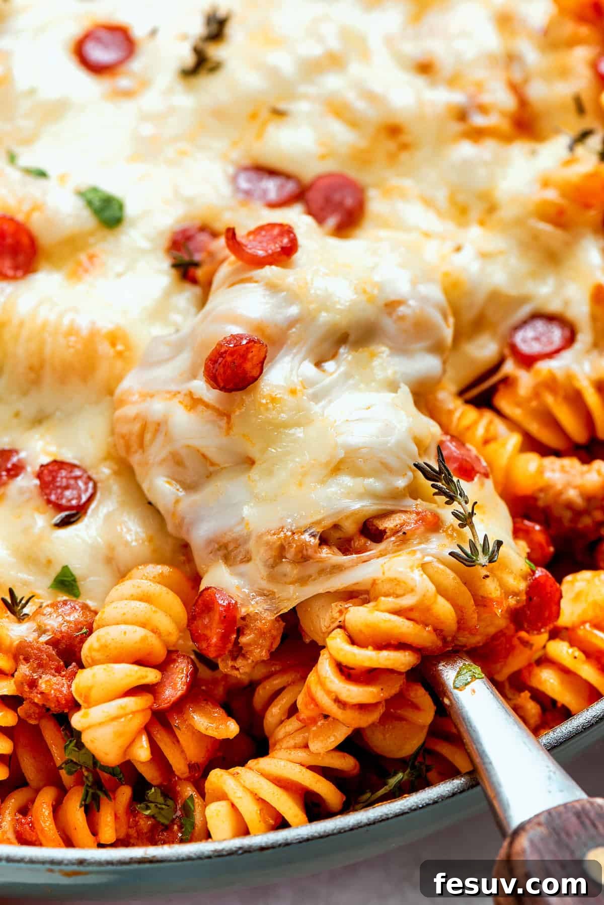 Close-up of stringy, melted mozzarella cheese on a pan of pizza pasta, showcasing its irresistible texture.