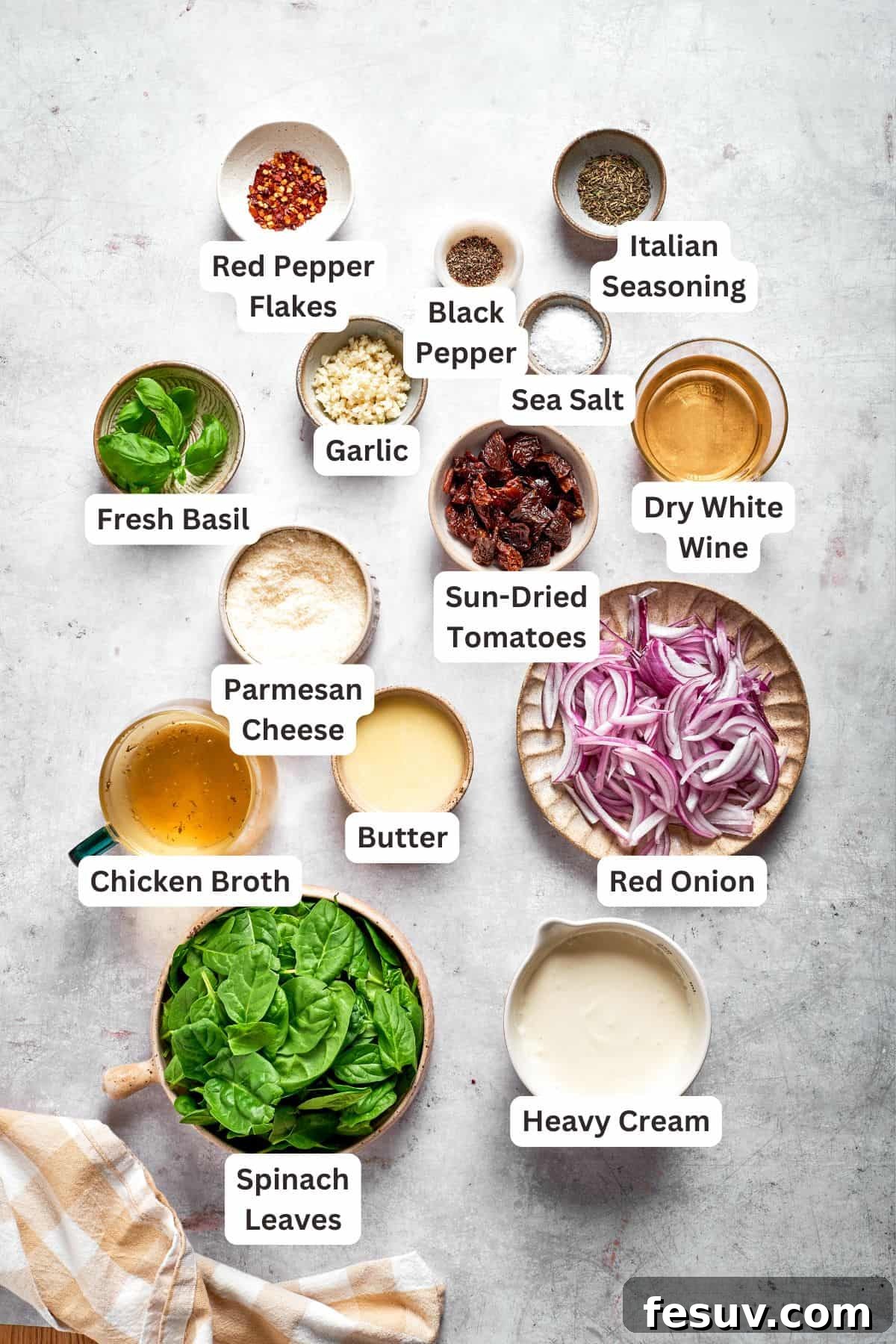 All the essential ingredients for Marry Me Chicken Pasta laid out on a table, including pasta, chicken, sun-dried tomatoes, spinach, garlic, onion, and various seasonings.