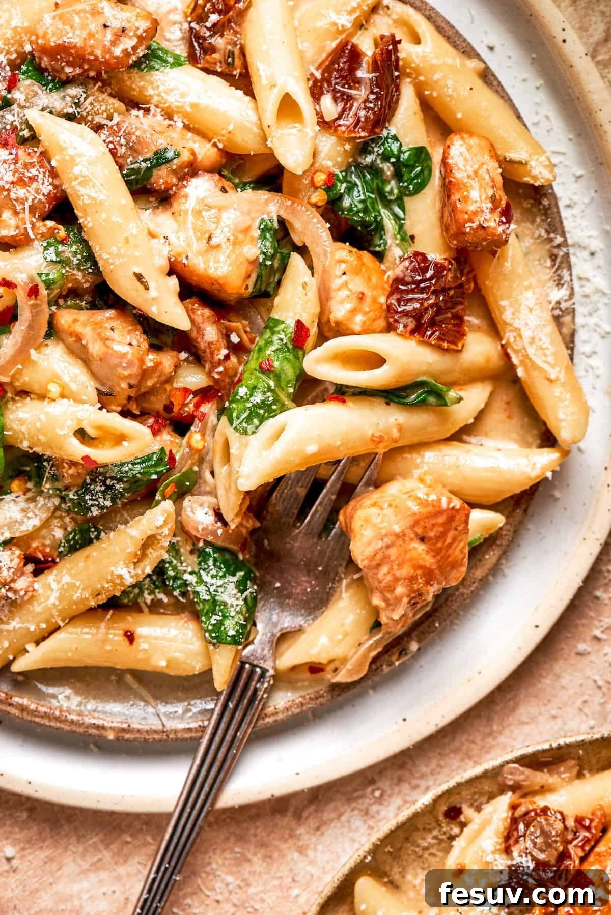 A fork piercing through a generous serving of Marry Me Chicken Pasta, highlighting the creamy sauce and chicken pieces.