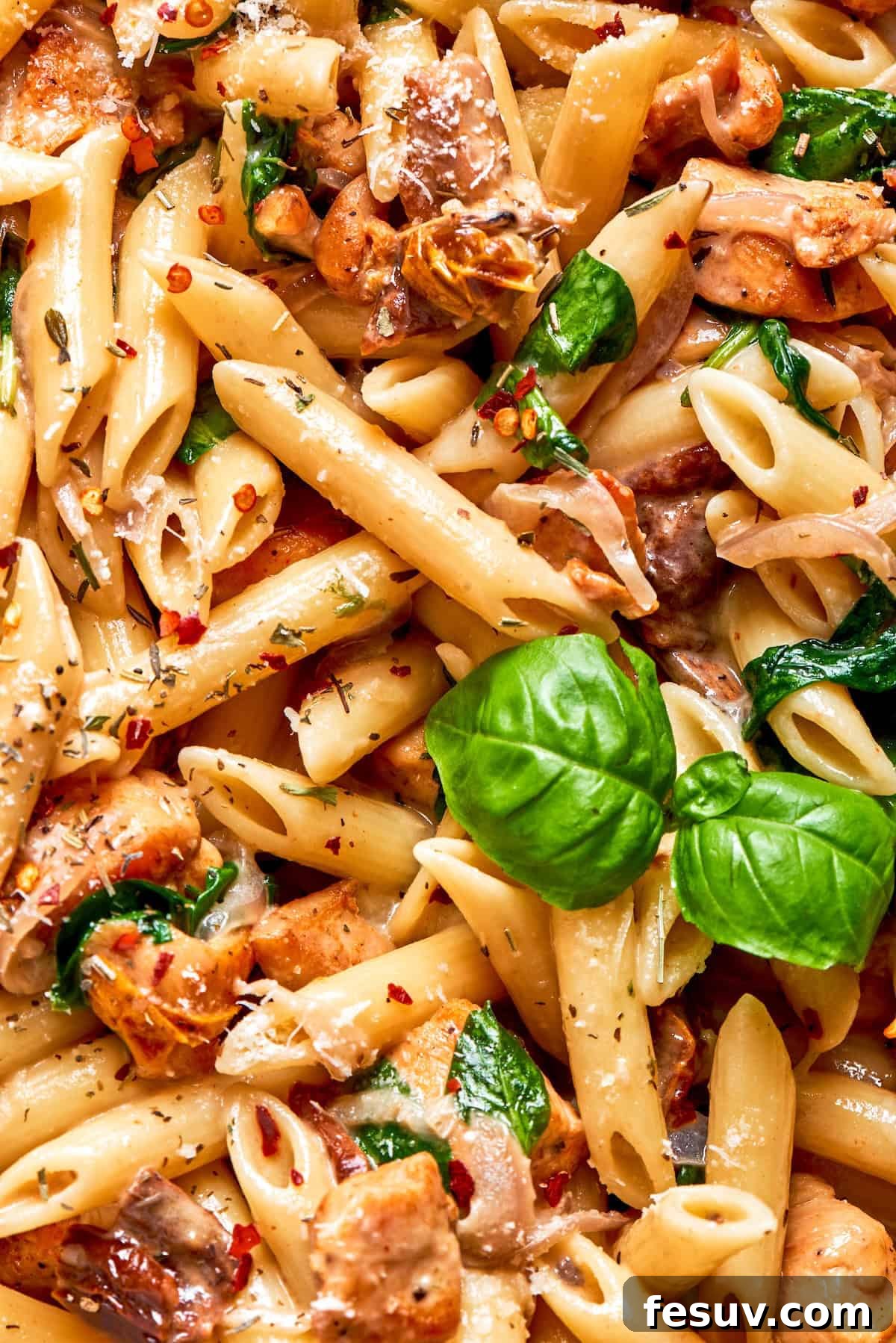 Close-up shot of uncooked penne pasta and fresh basil leaves, ready for Marry Me Chicken Pasta preparation.