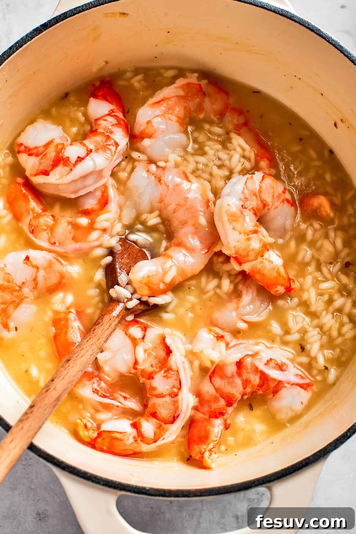 Adding shrimp to the simmering risotto during the final stages of cooking.