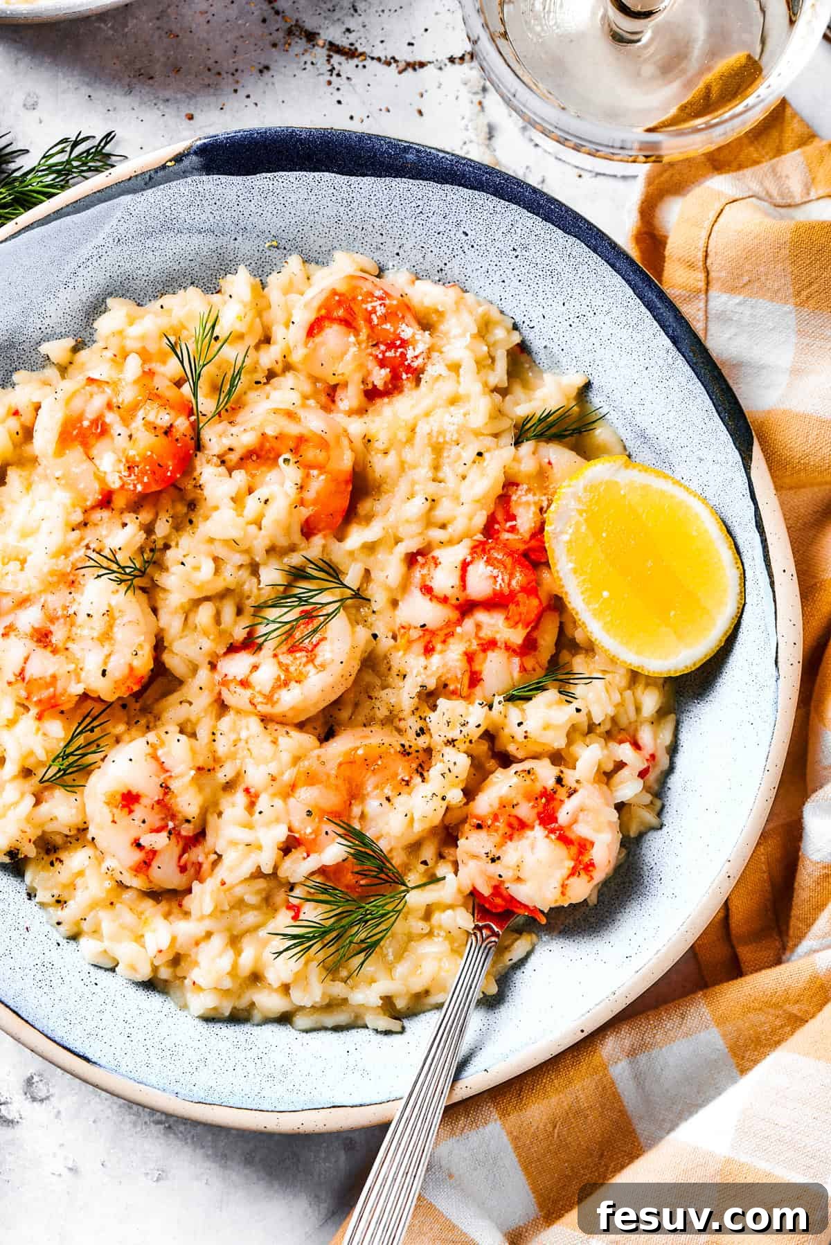 Shrimp risotto served on a plate with a wedge of lemon on the side.
