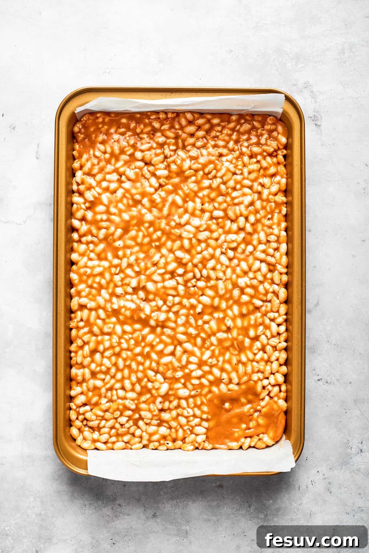 Golden Peanut Butter Crunch Bars 6 The Scotcharoos base, made of peanut butter and crispy rice cereal, is pressed evenly into a baking pan.
