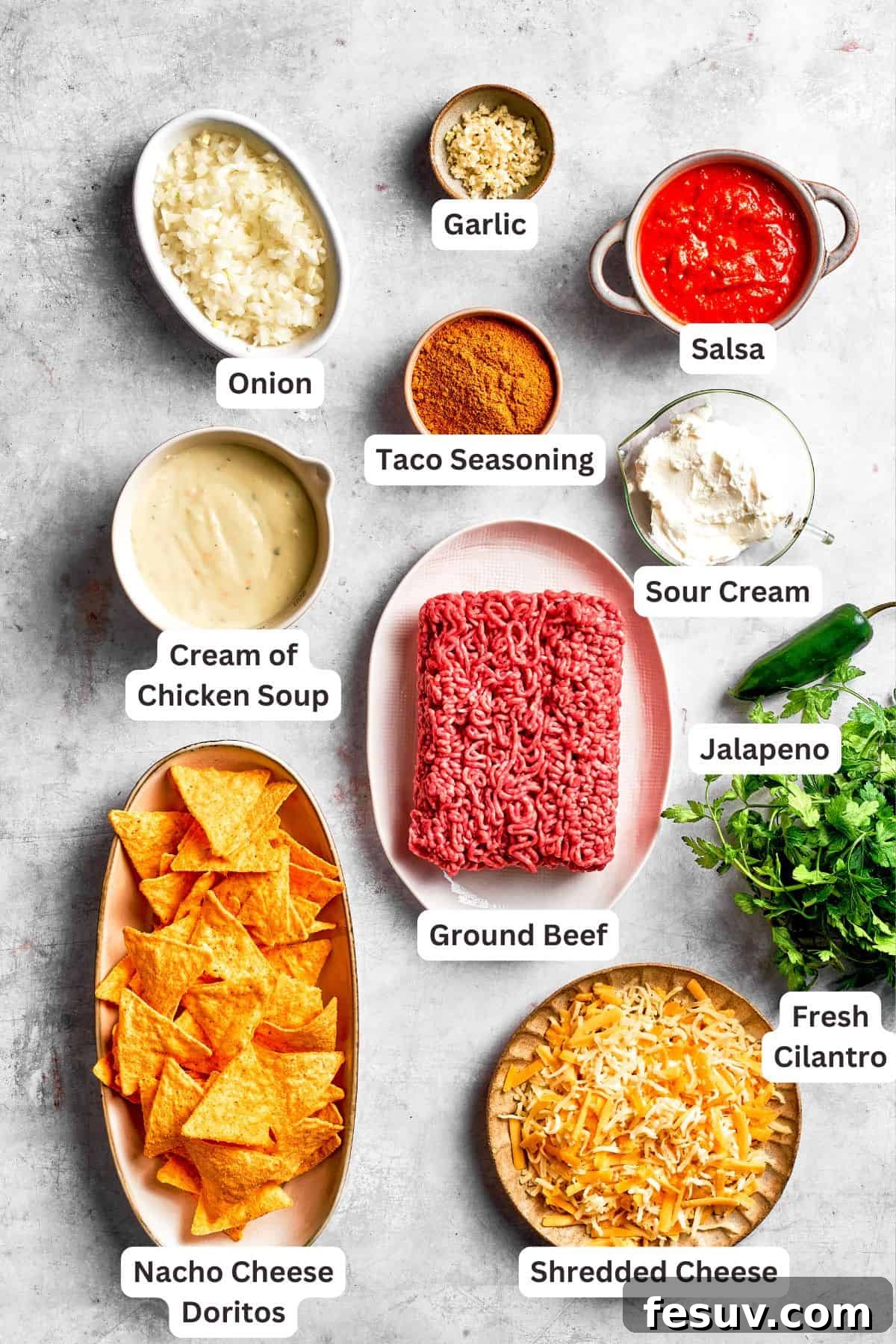 All the essential ingredients for Doritos casserole laid out on a table, clearly labeled for easy identification: yellow onion, garlic cloves, ground beef, taco seasoning, salsa, cream of chicken soup, sour cream, shredded cheese blend, Nacho Cheese Doritos, and fresh garnishes like green onions, cilantro, and cherry tomatoes.