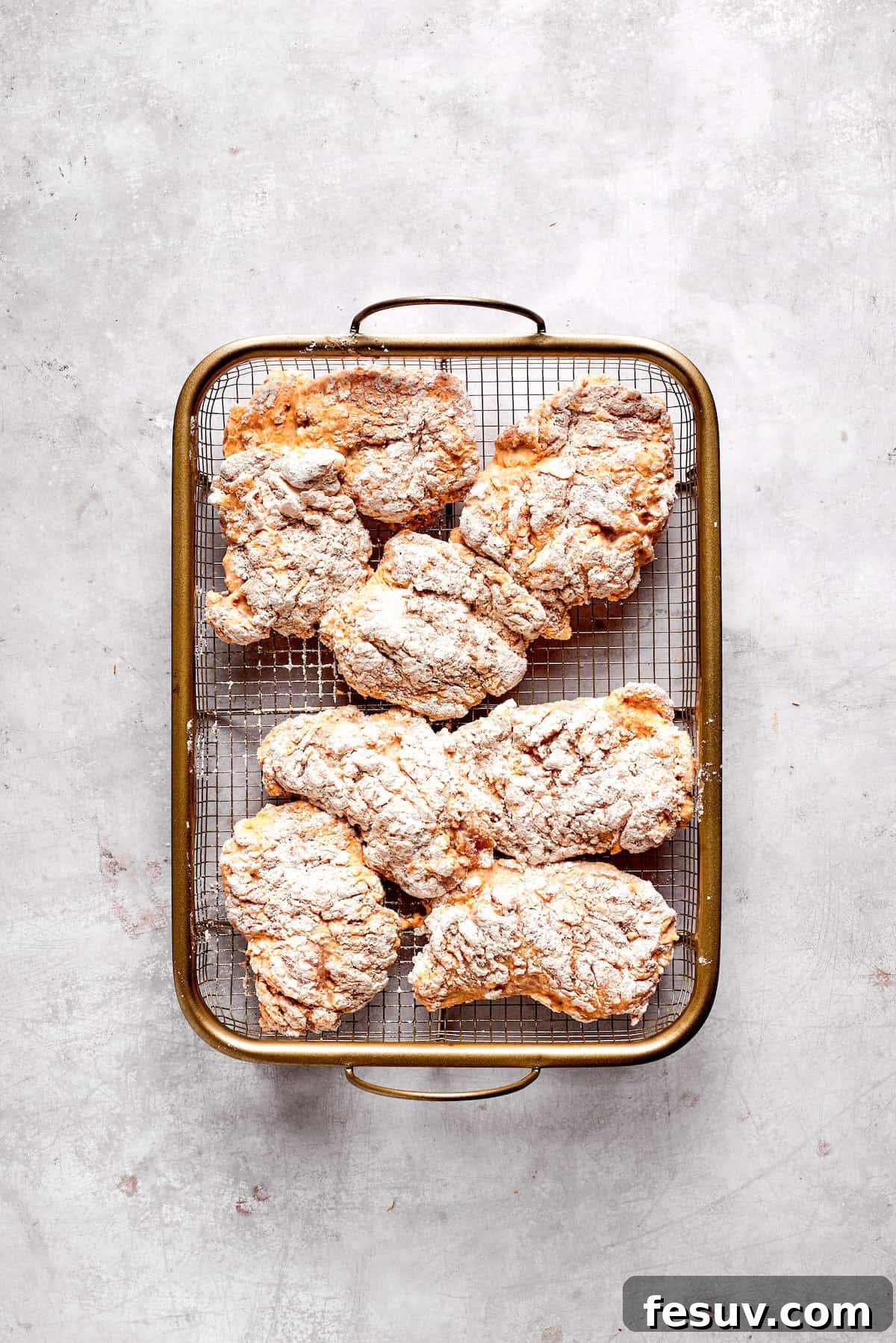 Resting Breaded Chicken for Crispy Fry Coated pieces of chicken resting on a wire rack, ready for frying.