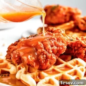 Pouring sauce over waffles and fried chicken.