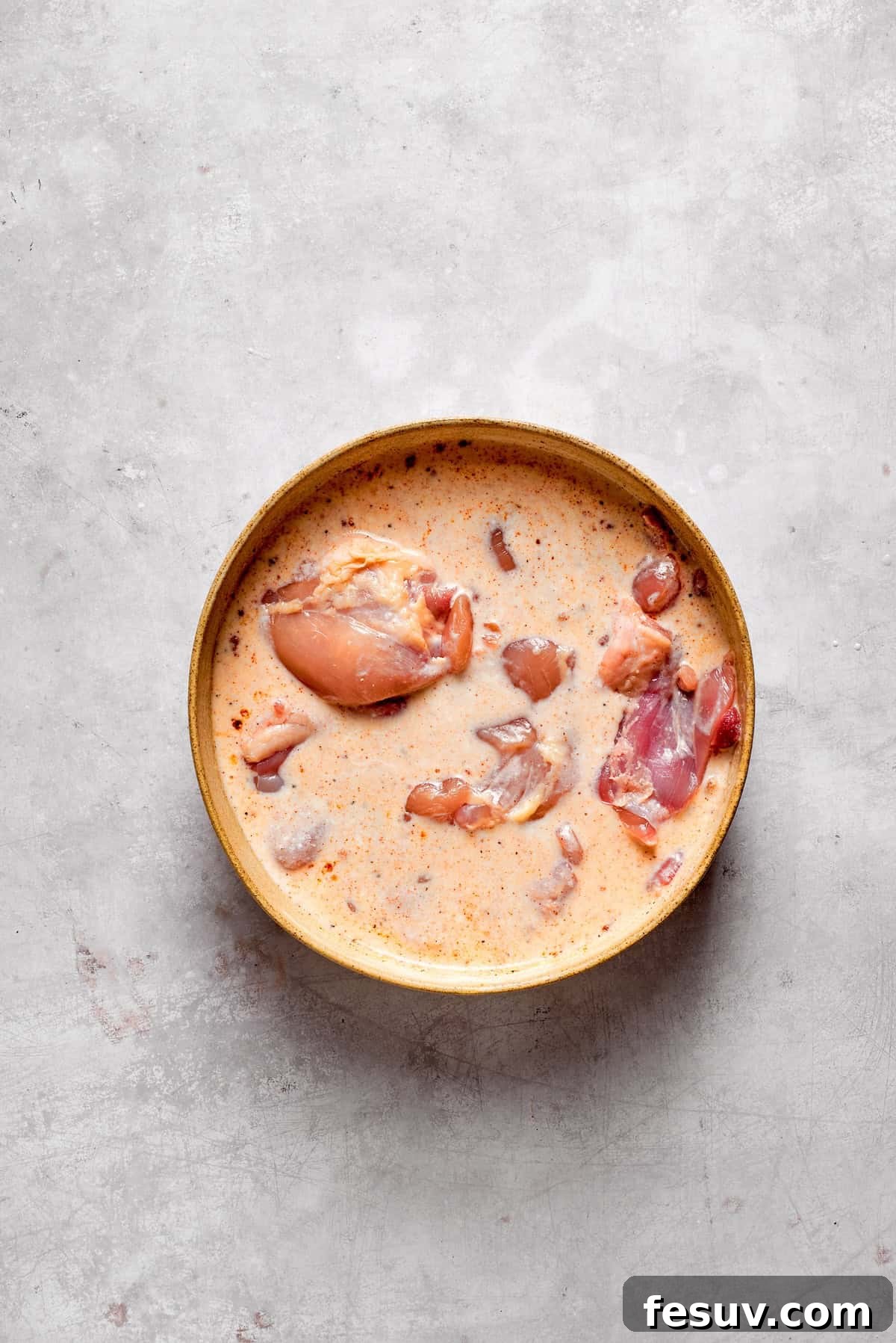 Marinating Chicken in Buttermilk for Tenderness Chicken thighs marinating in a creamy buttermilk mixture in a bowl.