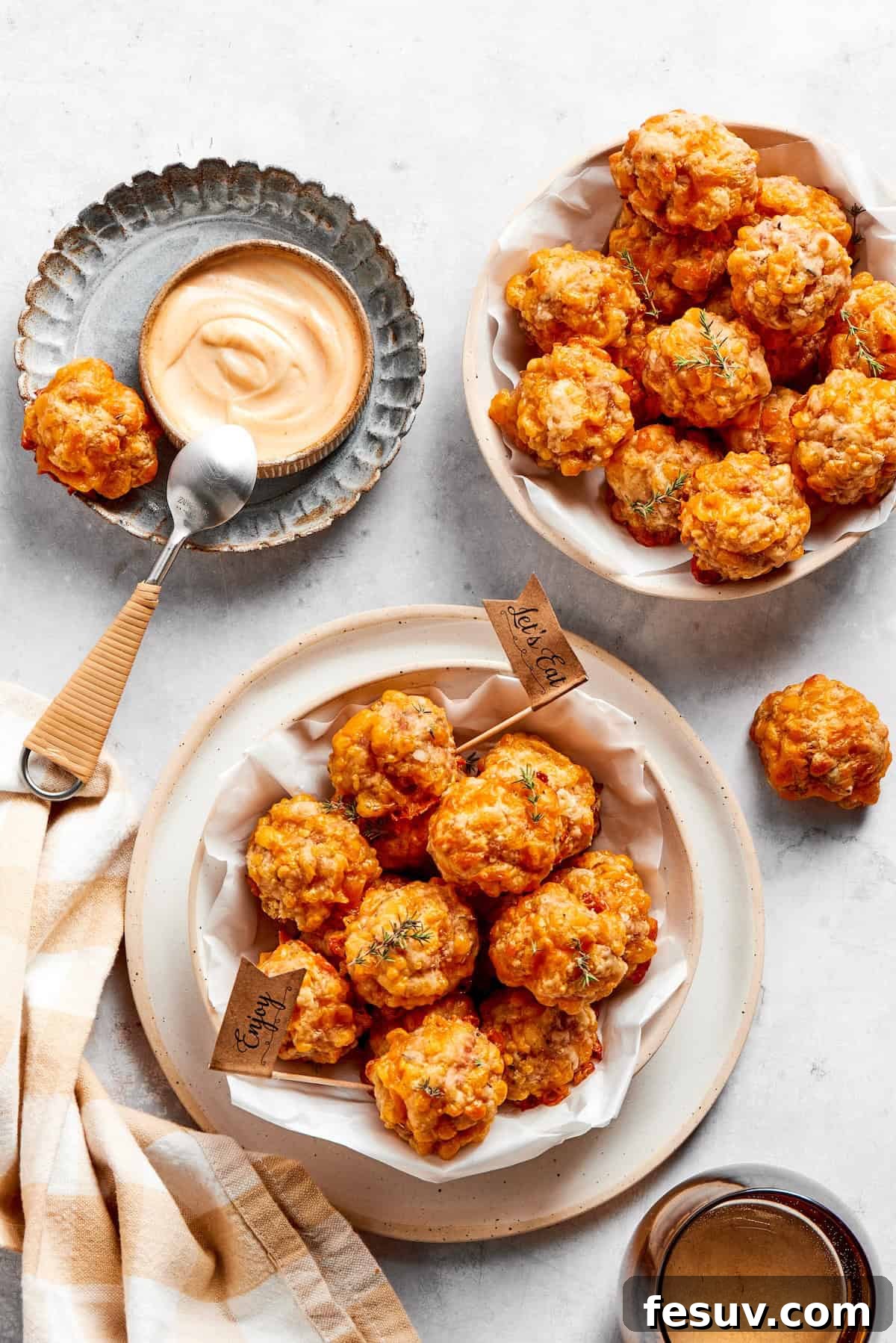 This sausage balls recipe relies on Bisquick, pork sausage, and Italian seasoning for an easy appetizer. Don't forget the dipping sauce! Two bowls of sausage balls and a bowl of dip and a spoon.
