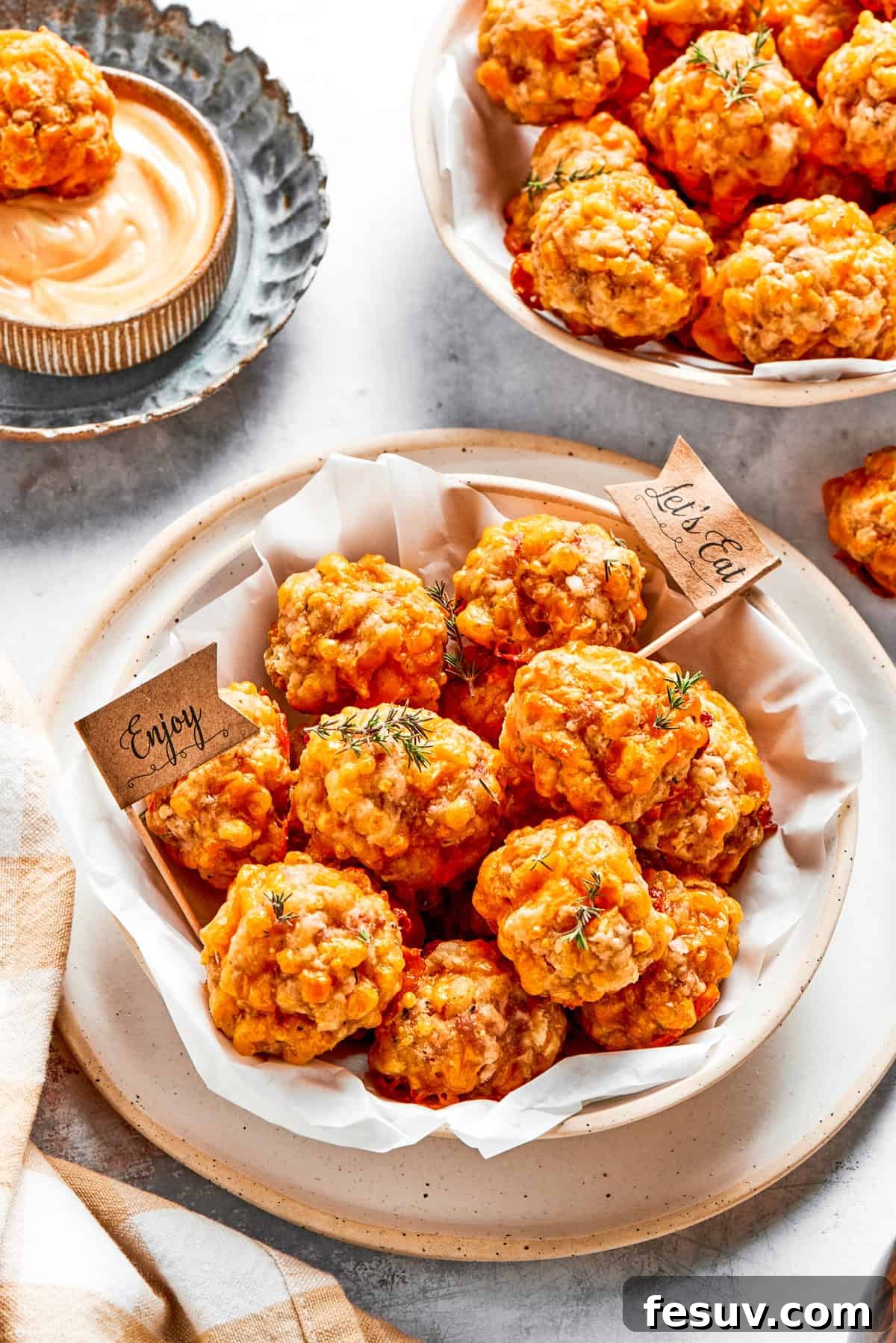 This sausage balls recipe relies on Bisquick, pork sausage, and Italian seasoning for an easy appetizer. Don't forget the dipping sauce! Two bowls filled with baked sausage balls.