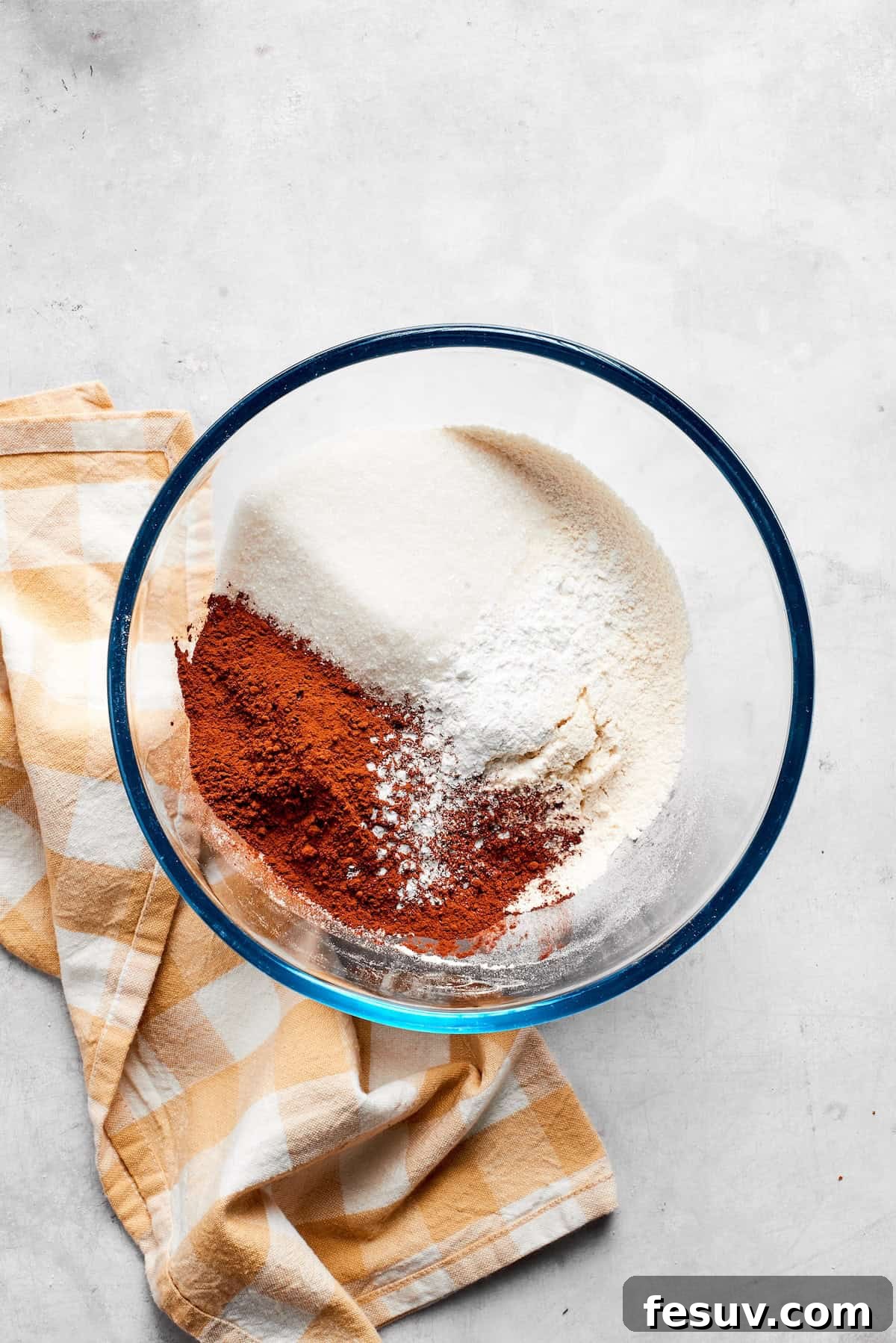 Dry ingredients for chocolate muffins are meticulously mixed in a large bowl, ensuring even distribution of flour, cocoa, sugar, baking powder, and salt.