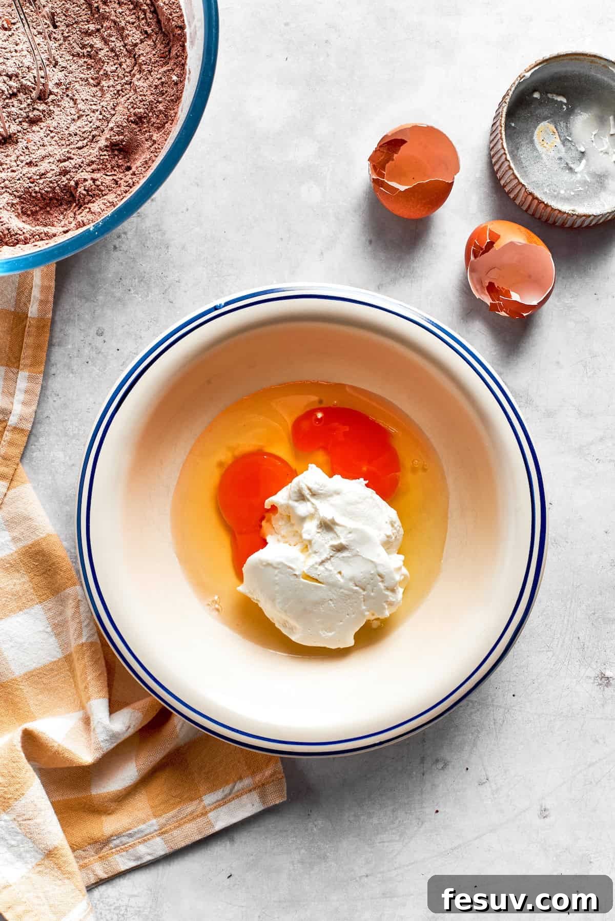 Eggs are expertly whisked with creamy sour cream in a separate bowl, preparing the wet base for the chocolate muffins.