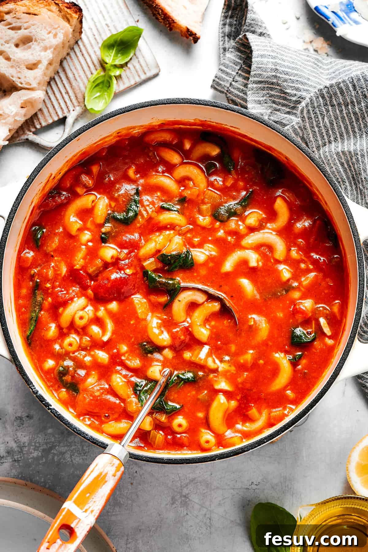 A large pot filled with steaming Tomato Florentine soup, showcasing the vibrant red broth, green spinach, and visible pasta and vegetables.