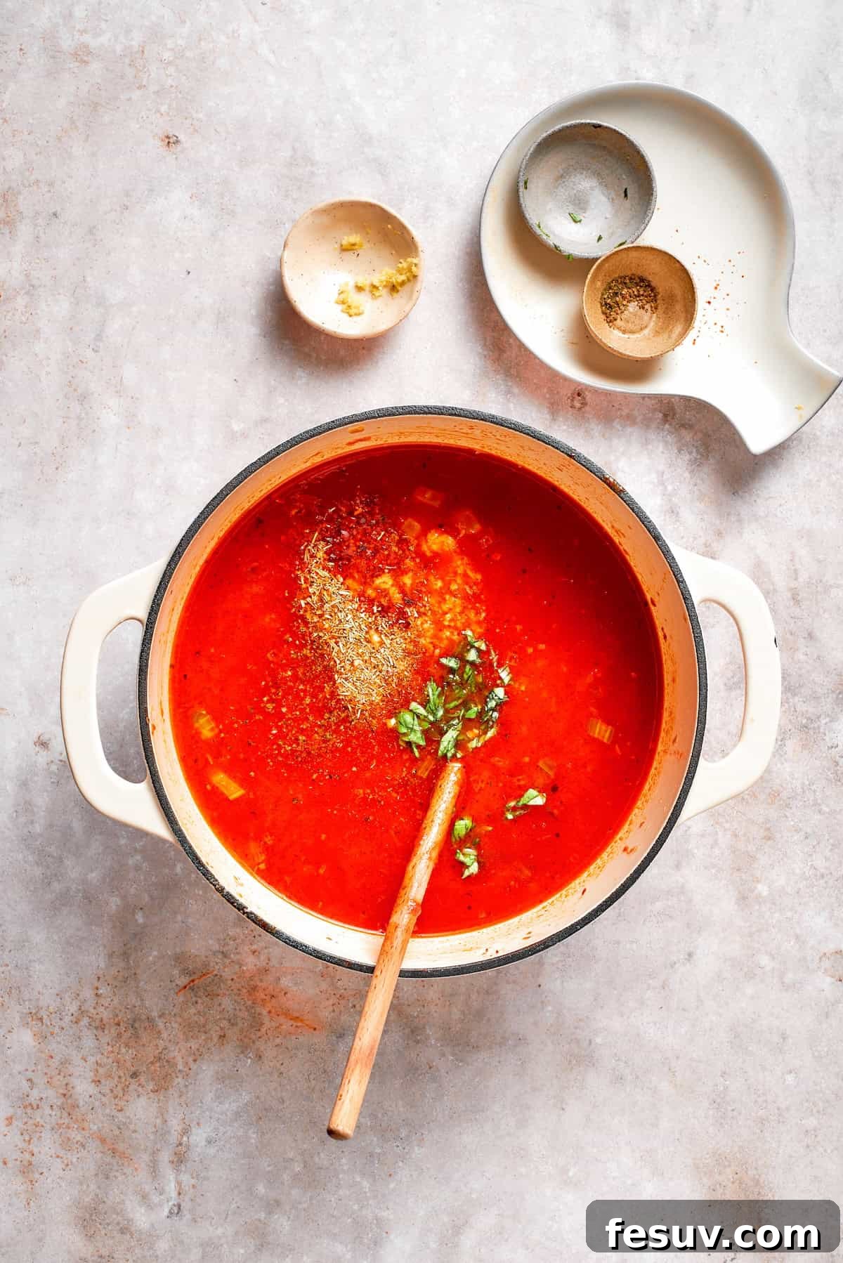 Broth, crushed tomatoes, and Italian herbs being added to the sautéed vegetable and tomato paste mixture in a large pot.