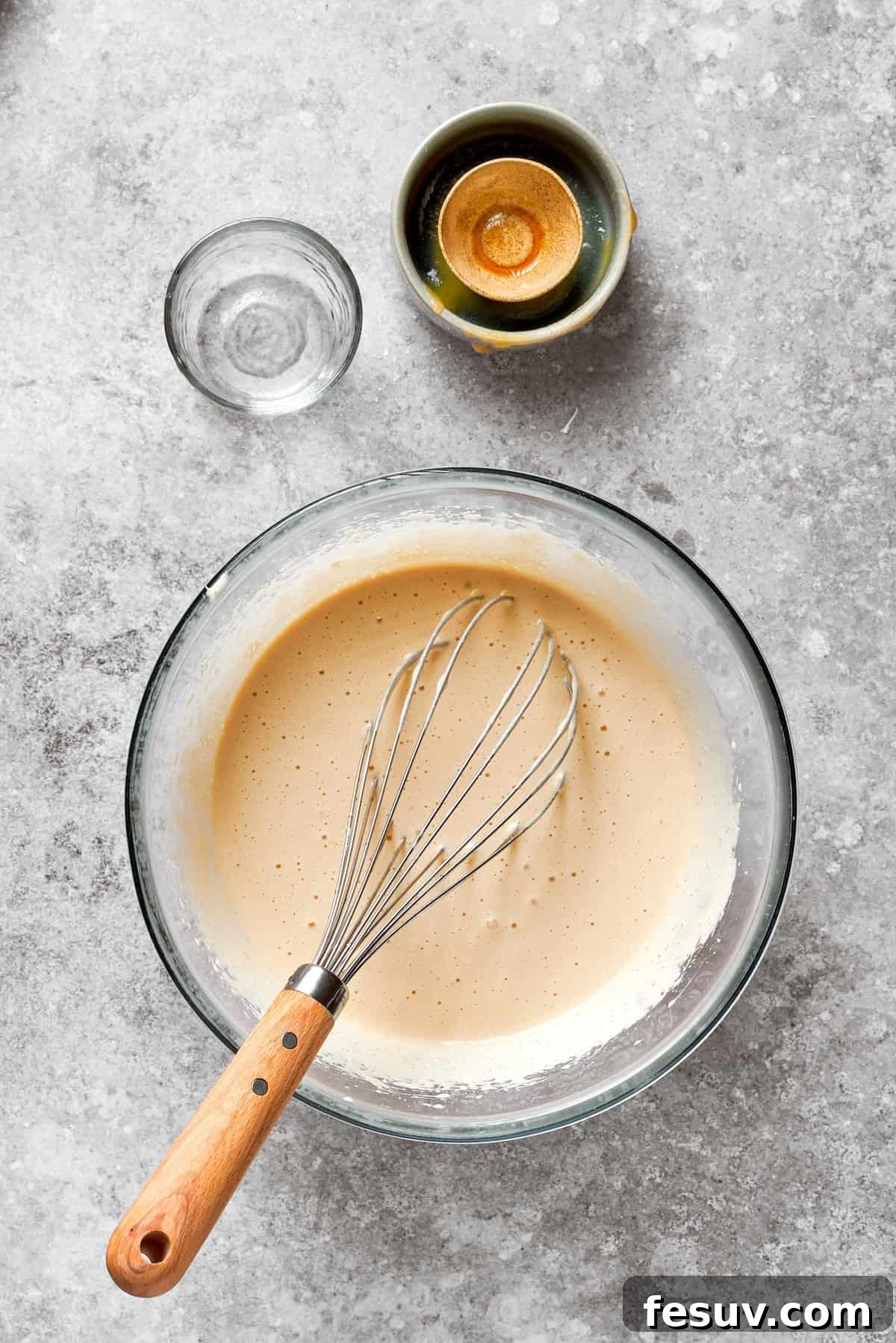 A whisk mixes the wet ingredients for carrot cake.