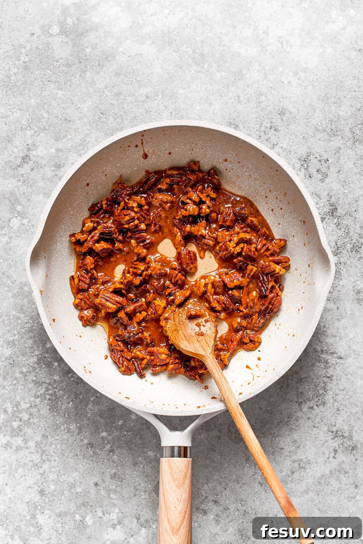 Pecans are toasted with butter in a skillet.