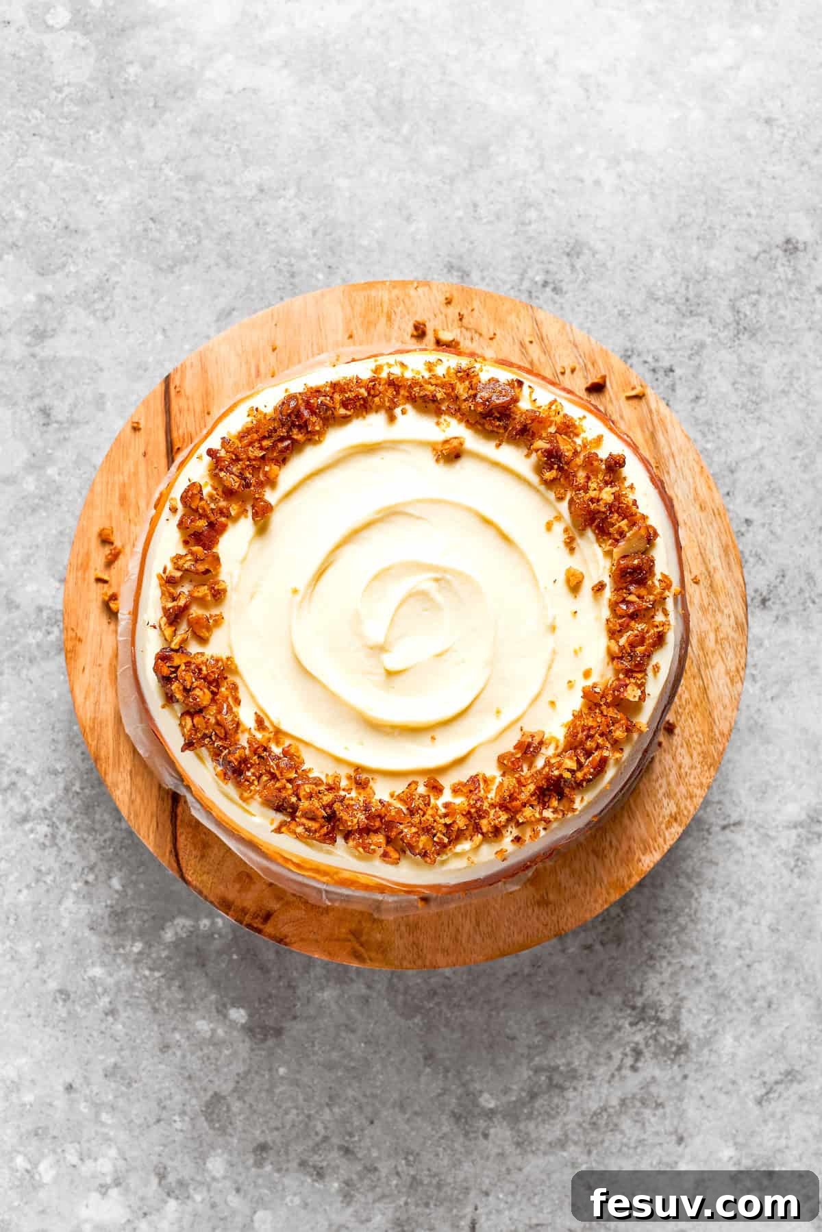 A carrot cake cheesecake on a wooden cake stand.