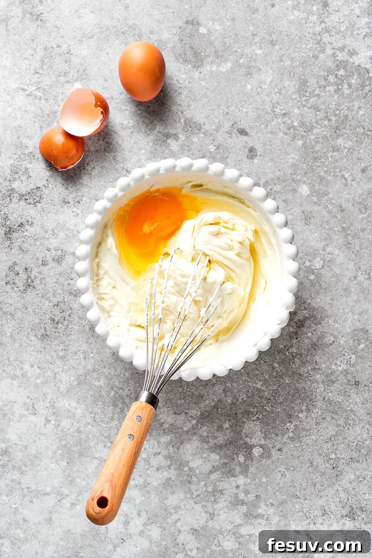 Eggs and cream cheese whisked in a bowl.