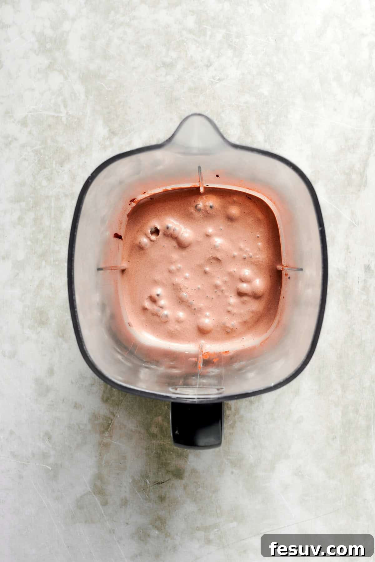 A high-powered blender actively blends a chocolate milkshake, creating a smooth and creamy mixture.