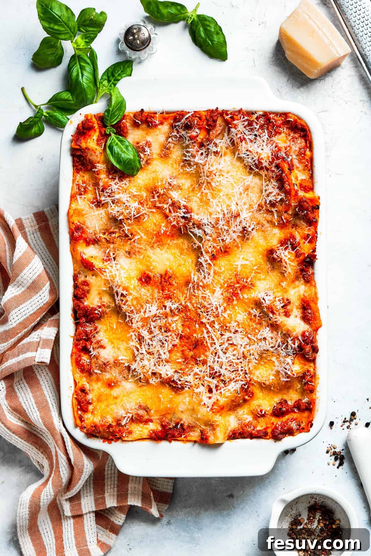 Overhead shot of a perfectly baked lasagna in a white baking dish, fresh from the oven.