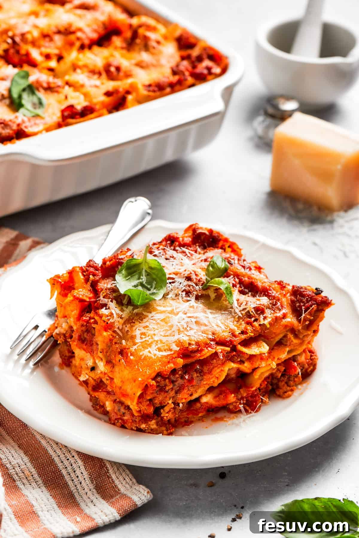 A serving of homemade beef lasagna served on a dinner plate with a fork, ready to eat.