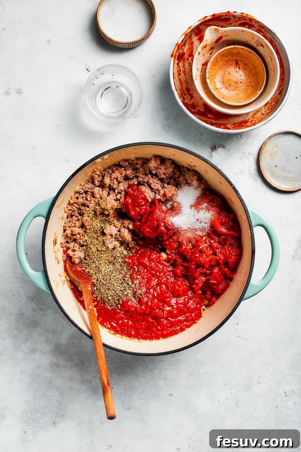 Sauce and tomato paste are added to a skillet with browned beef and aromatics.