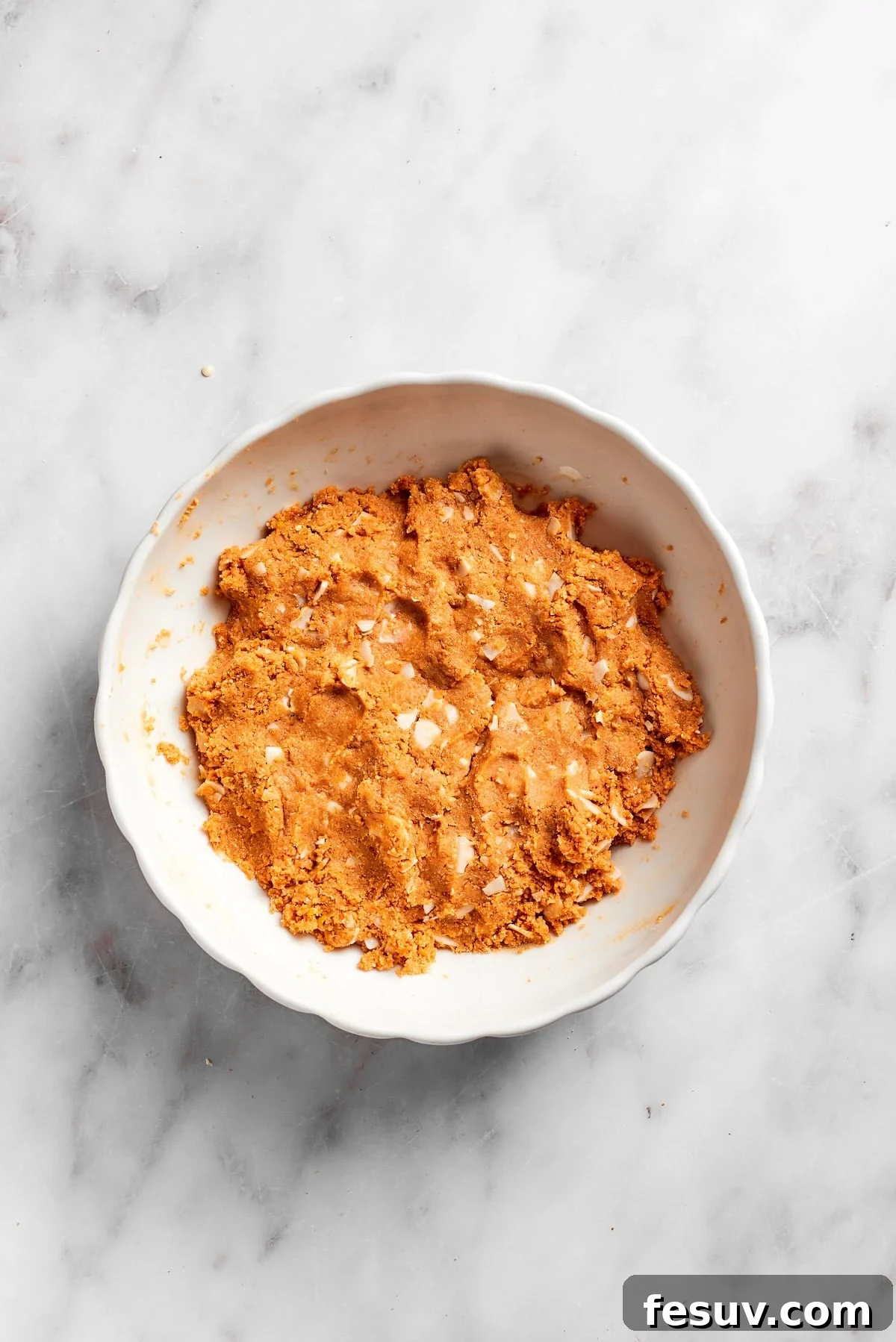 The fully mixed crust mixture for lemon slice in a bowl, ready for pressing.