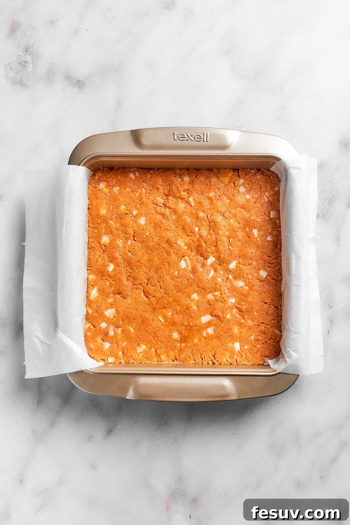 The graham cracker crust mixture firmly pressed into a lined baking pan.