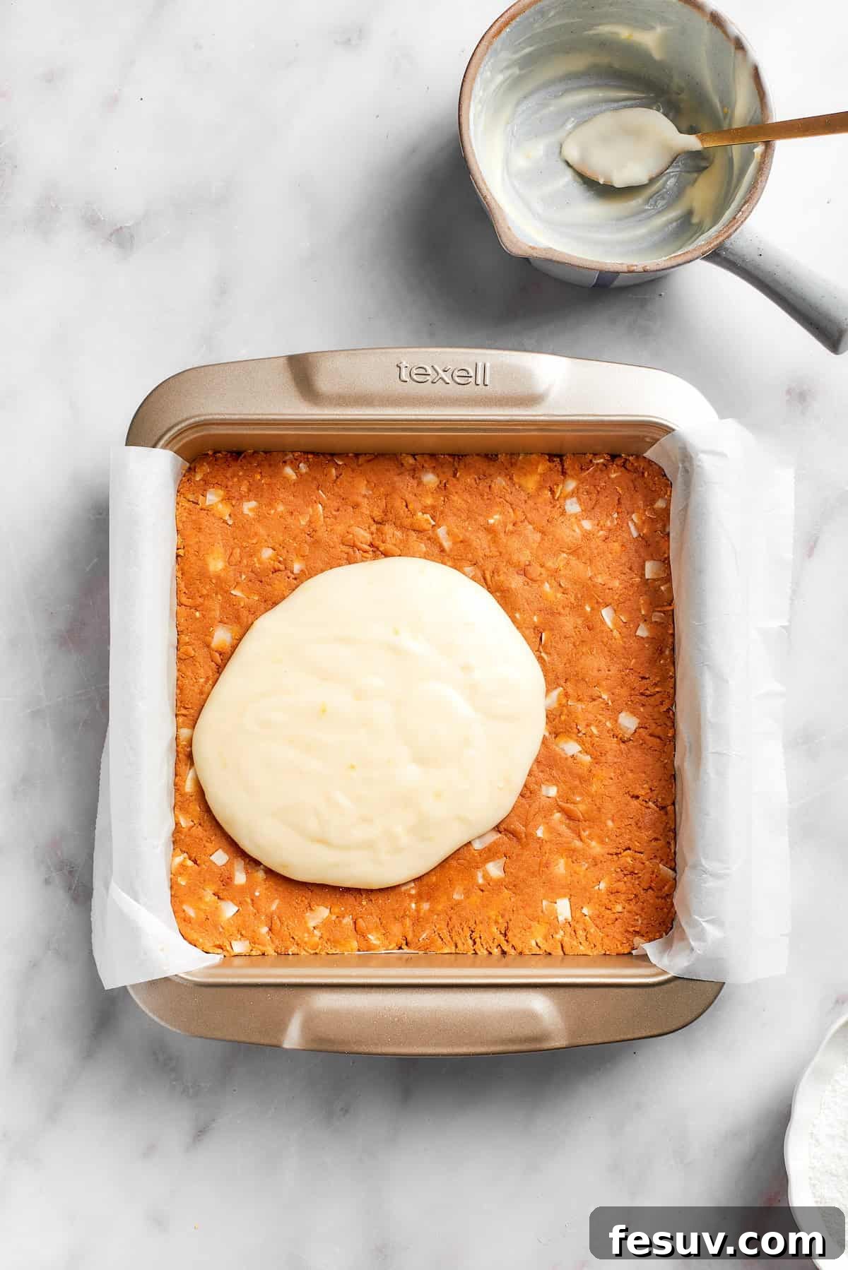 Smooth lemon frosting being spread over the chilled graham cracker crust.