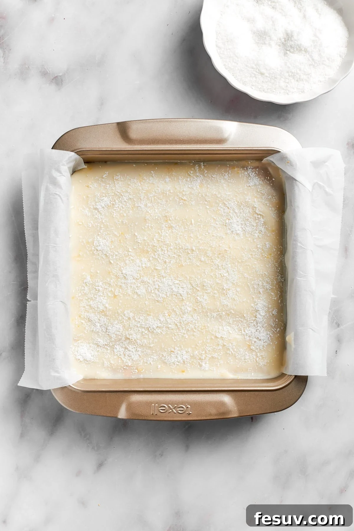The finished lemon slice in a lined pan, topped with coconut and ready for final chilling.