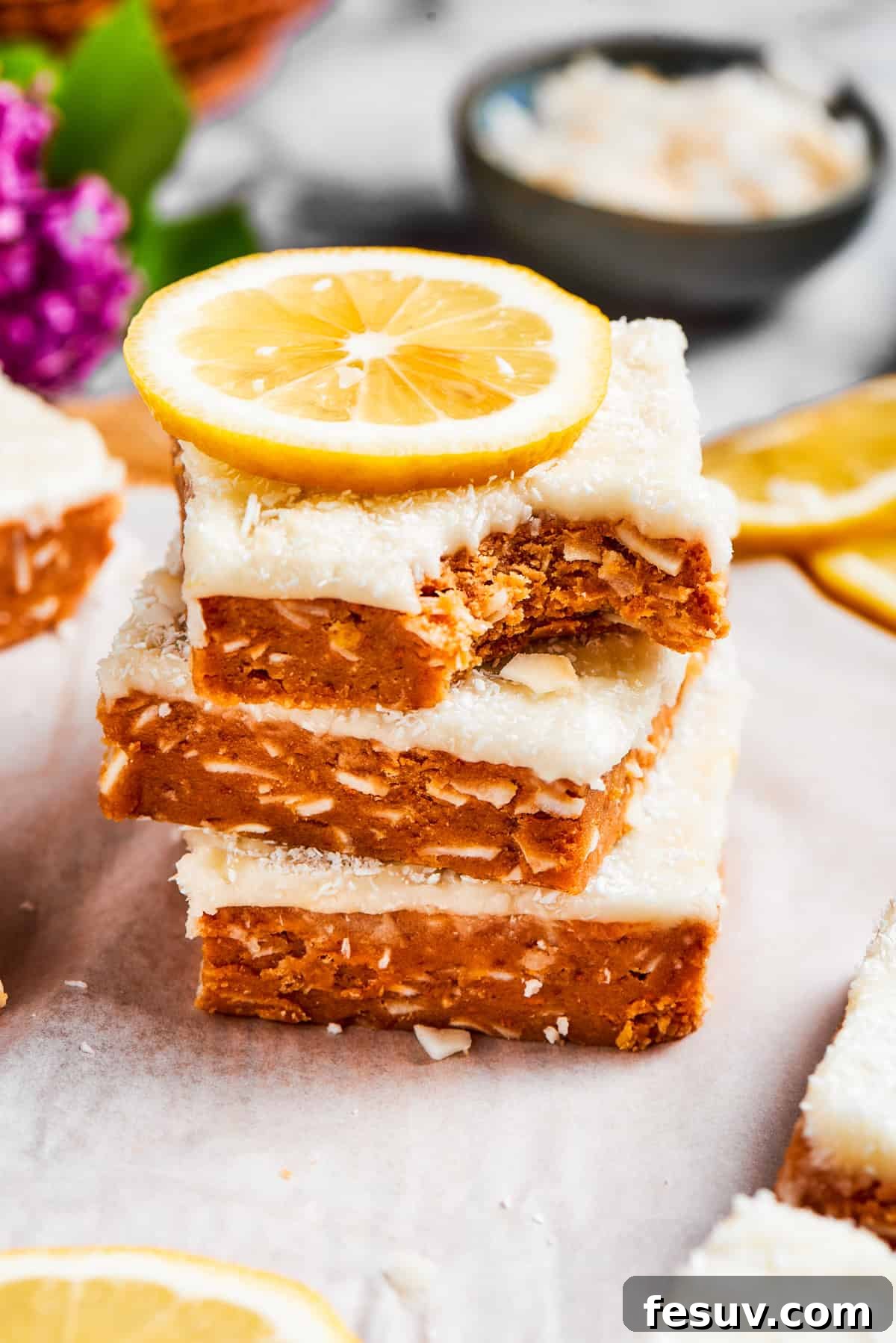 Three perfectly stacked lemon slice squares, with one showing a bite taken out, highlighting the layers.