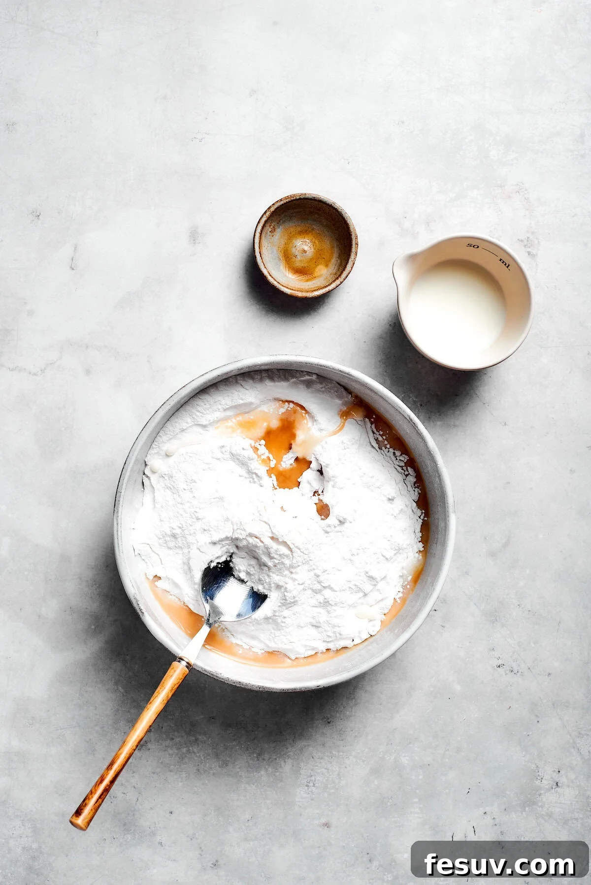 The 'Just One More' Cake 15 Confectioner's sugar, milk, and vanilla extract being whisked together in a bowl to create a smooth glaze.