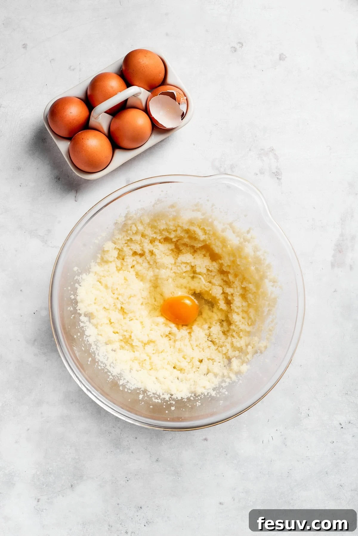 The 'Just One More' Cake 8 Eggs being carefully added one by one to a bowl of creamed butter and sugar in a stand mixer.