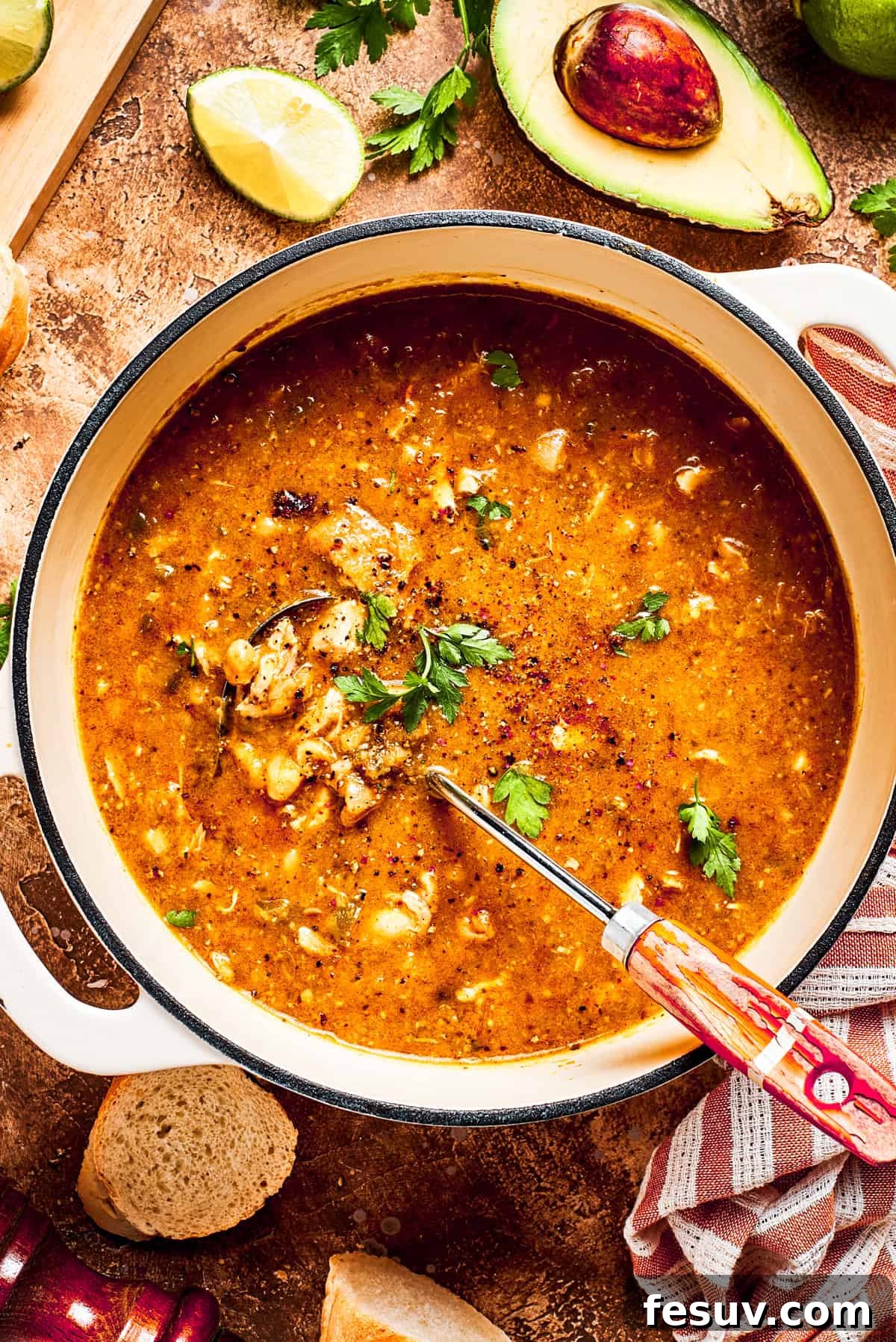 Tender chicken and pinto beans are cooked in a zesty broth made with salsa verde and green chilis to make spicy chicken soup. A pot of spicy chicken soup is mixed to combine all the ingredients.