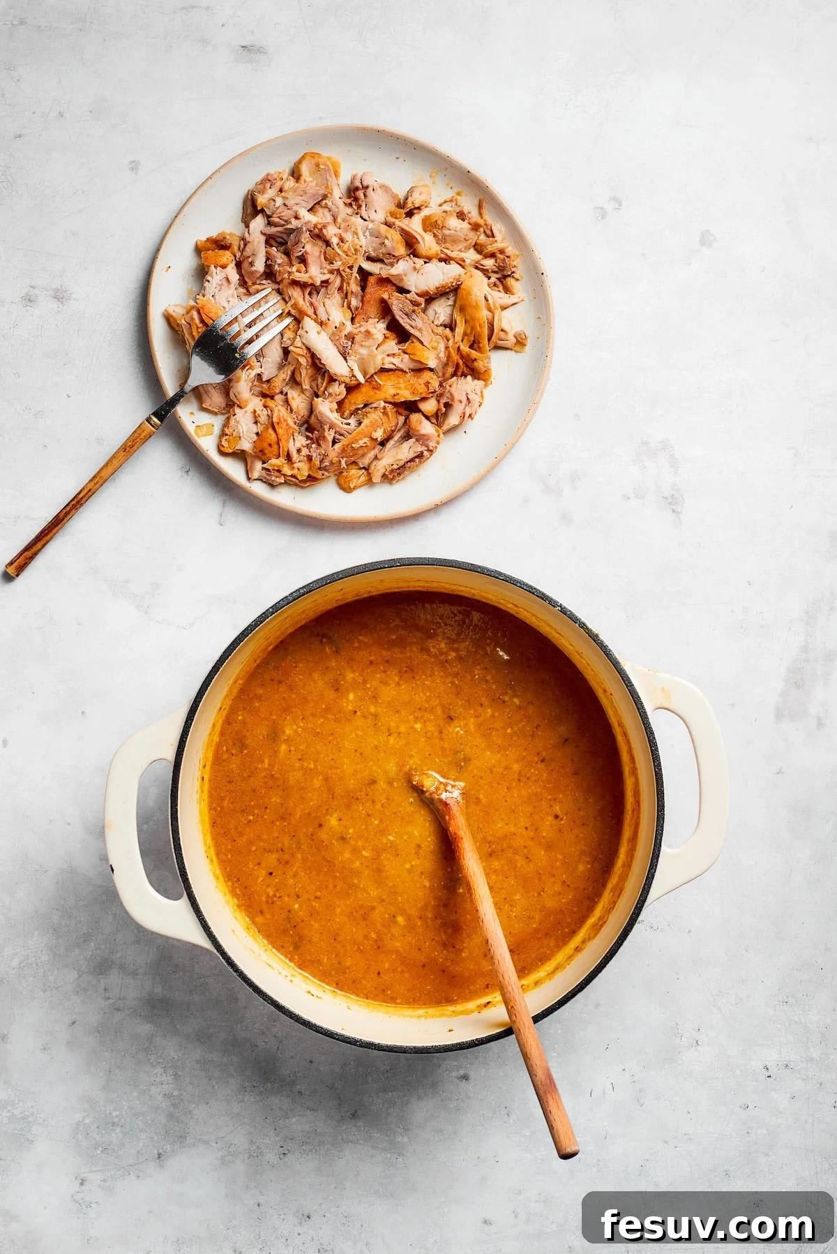 Tender chicken and pinto beans are cooked in a zesty broth made with salsa verde and green chilis to make spicy chicken soup. A plate of shredded chicken next to a pot of soup.