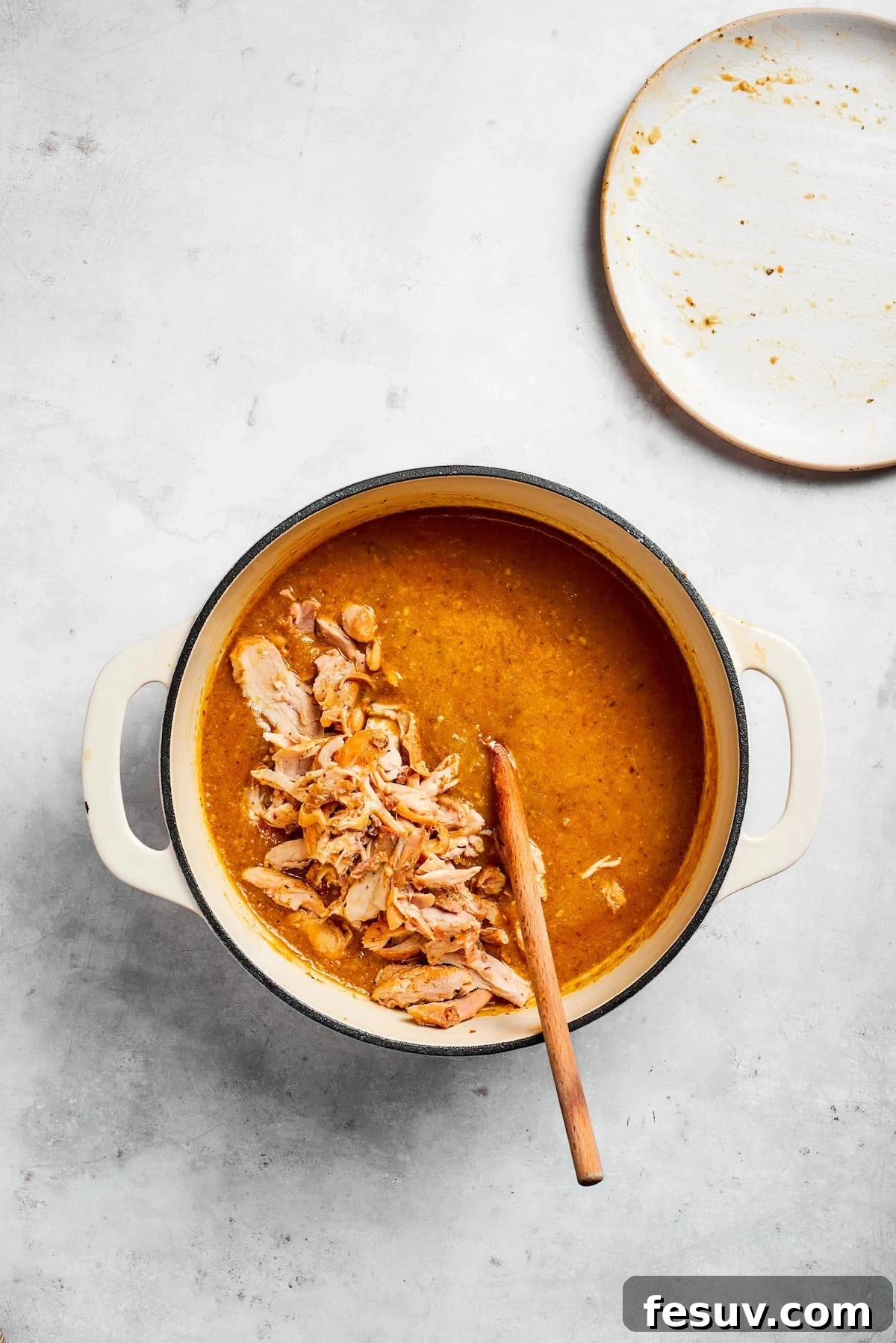 Tender chicken and pinto beans are cooked in a zesty broth made with salsa verde and green chilis to make spicy chicken soup. Chicken is added back into a soup pot.
