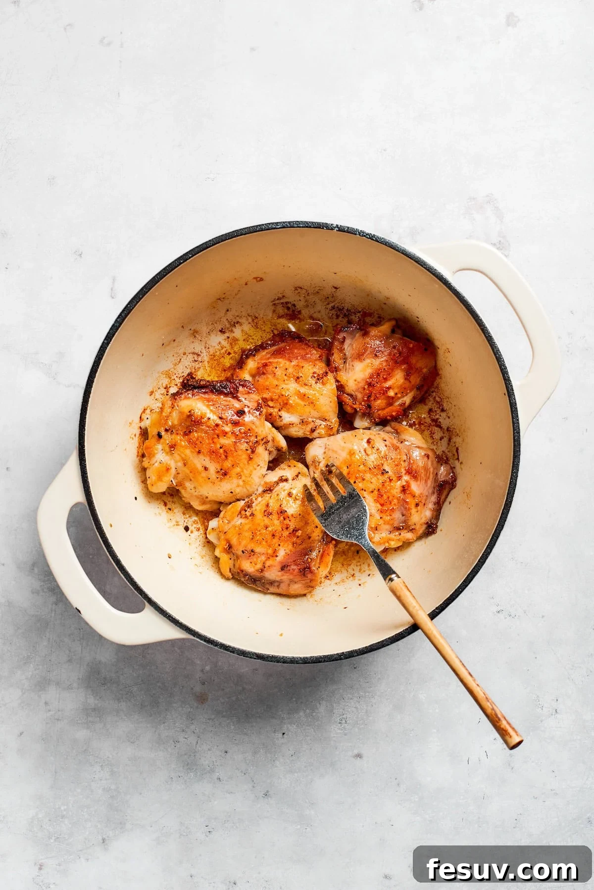 Tender chicken and pinto beans are cooked in a zesty broth made with salsa verde and green chilis to make spicy chicken soup. A fork moves chicken in a pot.