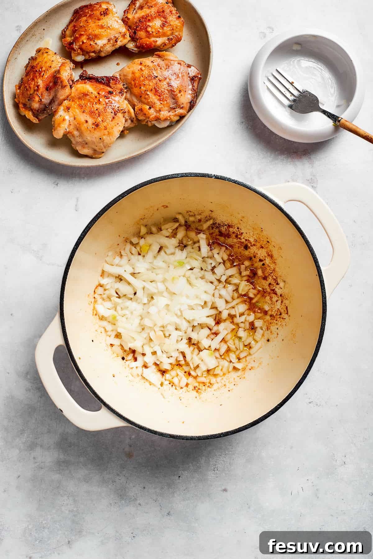 Tender chicken and pinto beans are cooked in a zesty broth made with salsa verde and green chilis to make spicy chicken soup. Garlic and onion are added to a pot.