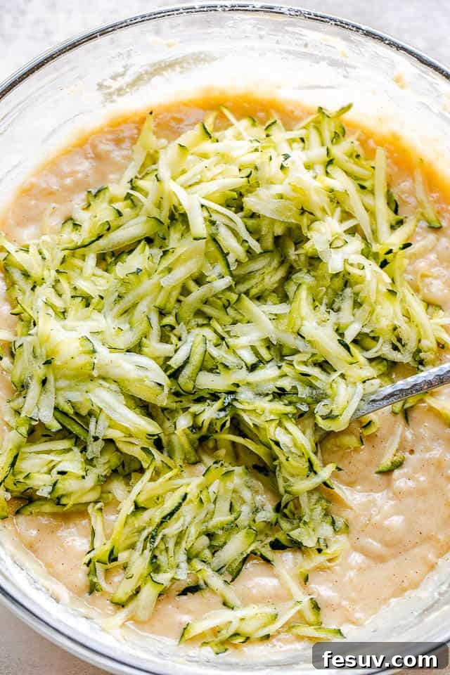 glass mixing bowl with shredded zucchini batter for bread