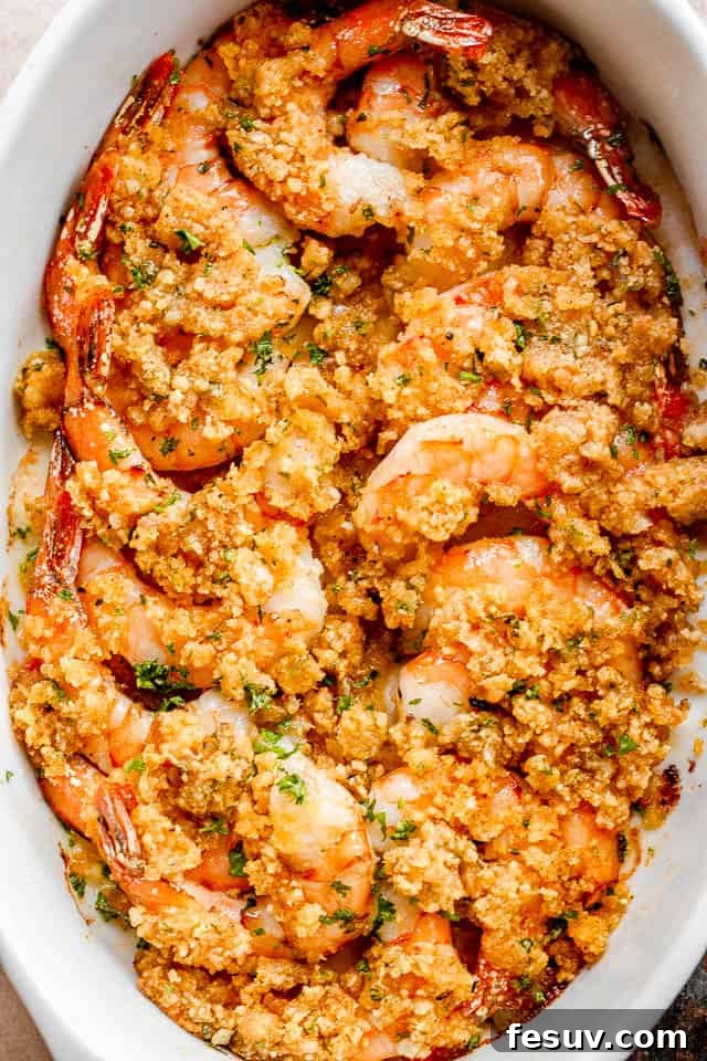 Garlic Butter Baked Shrimp De Jonghe 2 overhead shot of arranged shrimp in a white oval dish and topped with garlic butter and breadcrumbs mixture.