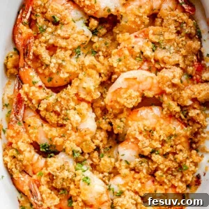 Garlic Butter Baked Shrimp De Jonghe 8 overhead shot of arranged shrimp in a white oval dish and topped with garlic butter and breadcrumbs mixture