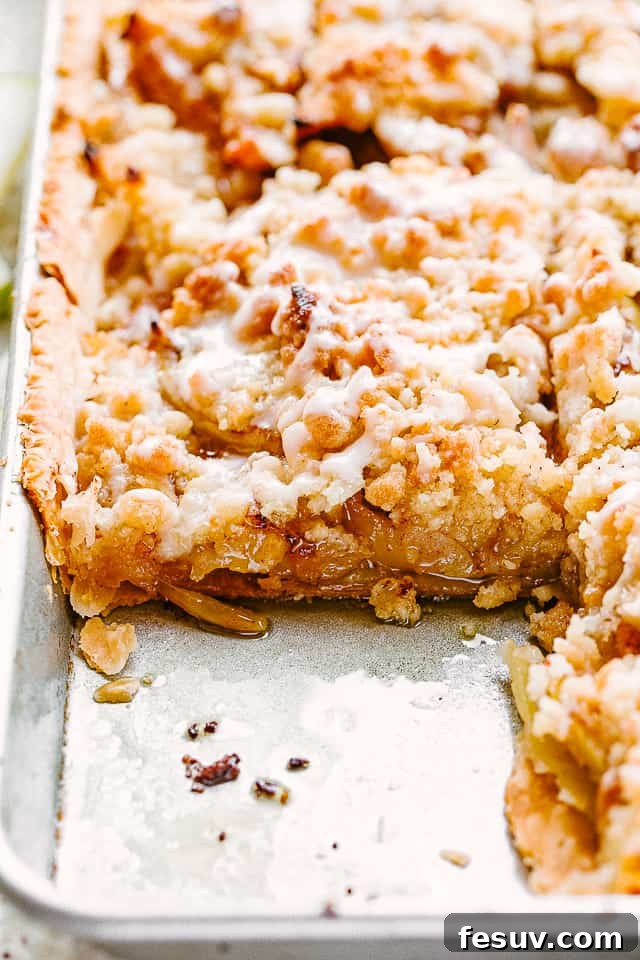 A beautiful side shot of a perfectly baked Dutch apple slab pie resting in a sheet pan, ready to be sliced.