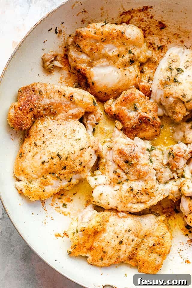 Overhead shot of boneless skinless chicken thighs in a white skillet before cooking