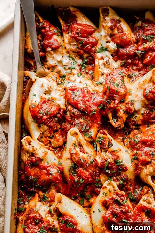 close up top view of pasta shells stuffed with beef and topped with shredded cheese and marinara
