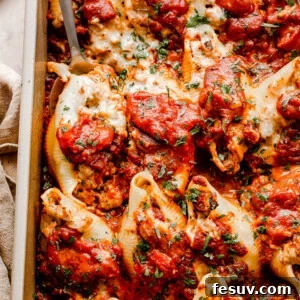 close up top view of pasta shells stuffed with beef and topped with shredded cheese and marinara