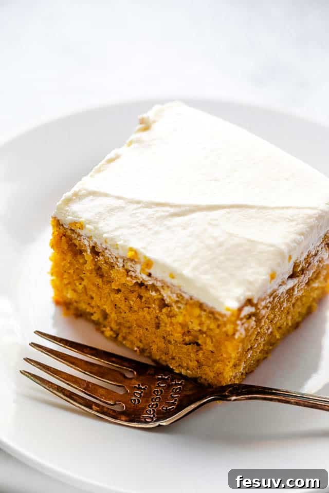 A slice of frosted pumpkin bar on a plate with a fork, ready to be enjoyed.