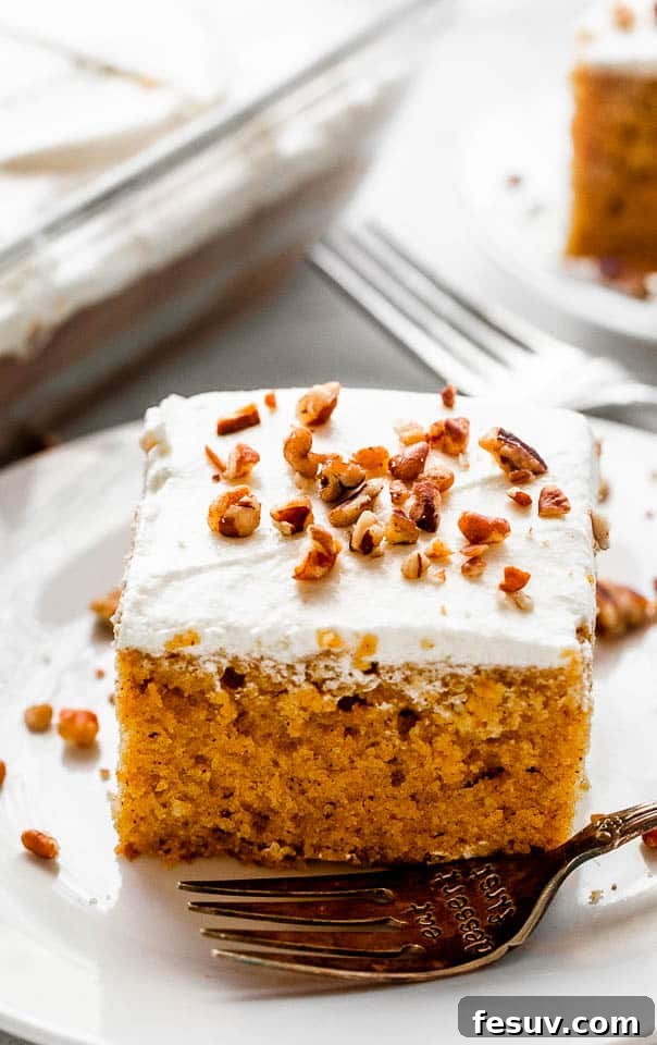 Close-up of a single slice of pumpkin bar topped with cream cheese frosting and chopped pecans, ready to eat.