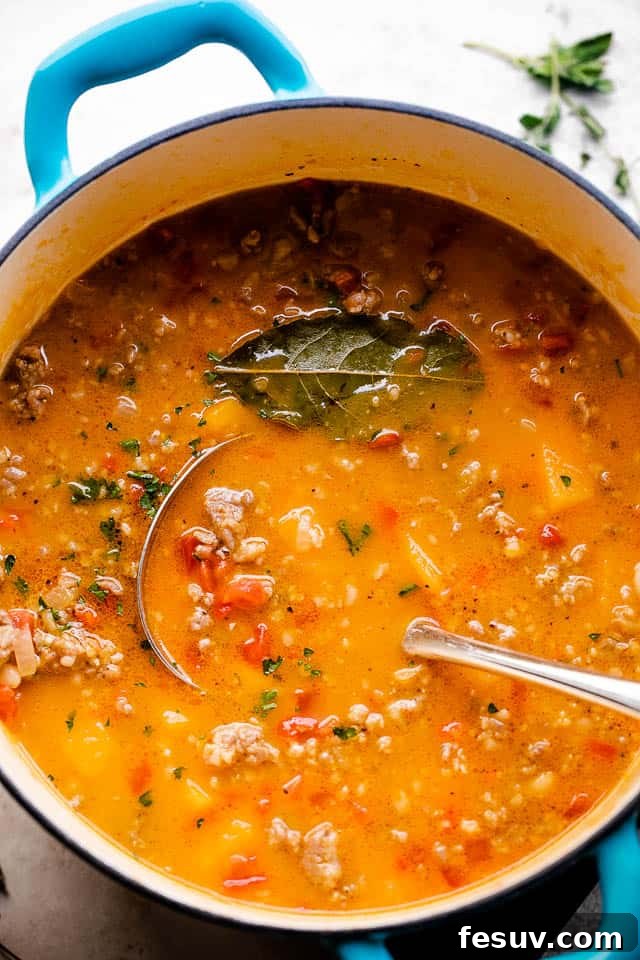 Butternut squash soup with Italian sausage soup in a Dutch oven with a ladle inside the soup.