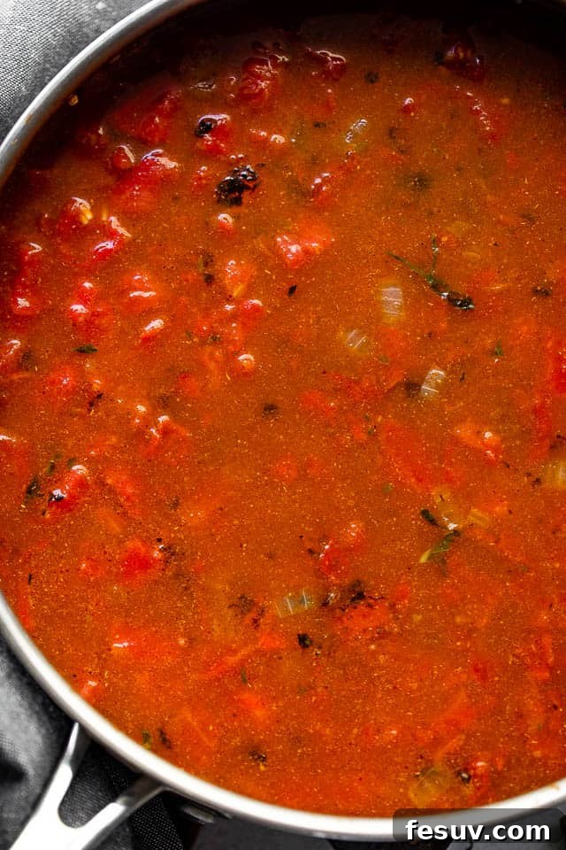 Tomato sauce cooking in a stainless steel skillet.