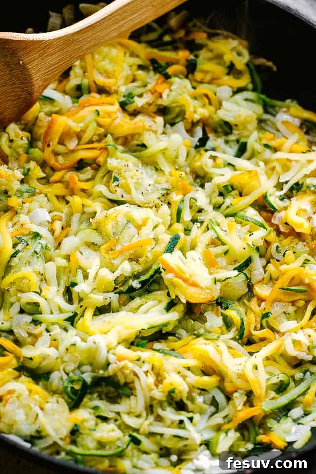sauteeing spiralized zucchini in a black frying pan